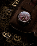 Seagull 1963 Legacy Burgundy inside a brown suede pouch set on a bed of loose brass gears