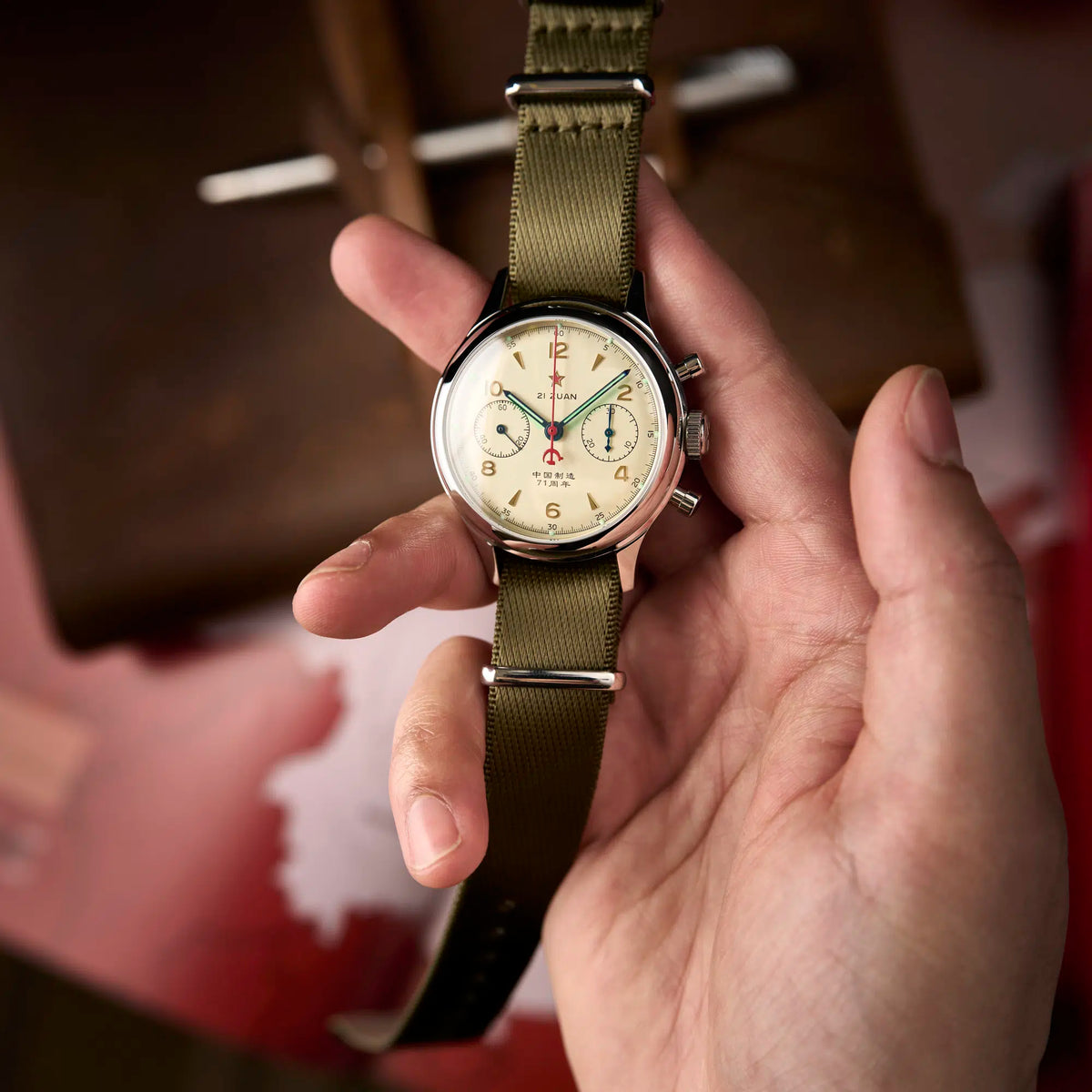 Seagull 1963 Lume 38mm held in a hand, cream dial with the 71st anniversary line, pale green lume hands, red backdrop
