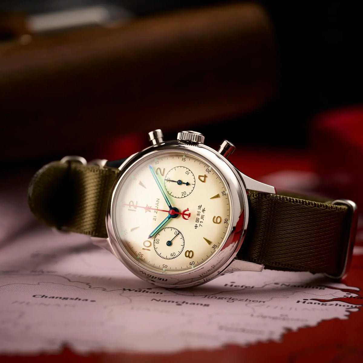 Seagull 1963 Lume 38mm on olive NATO laid over a red map of China, crown and pushers on the right