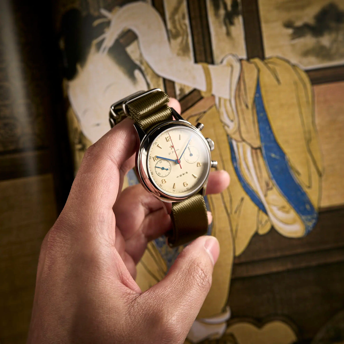 Seagull 1963 cream dial chronograph held in a hand, angled to show the crown and both pushers