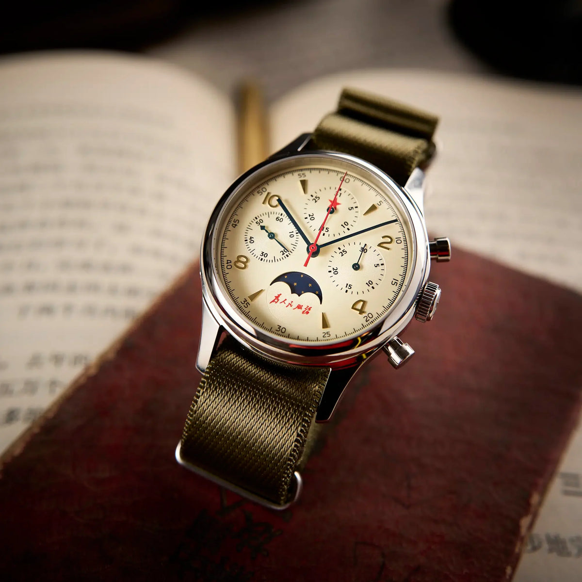 Seagull 1963 Moonphase Cream at an angle on a red book, gold numerals and the moon aperture in view