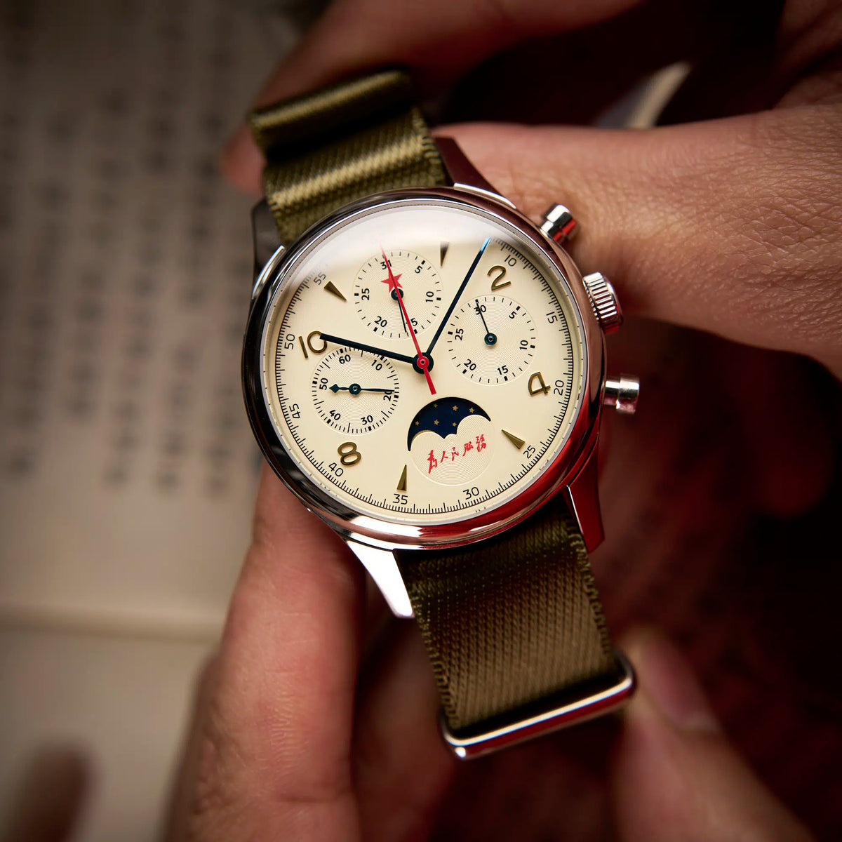 Seagull 1963 Moonphase Cream dial held between fingers, pointer date at 12 and the moon window at 6