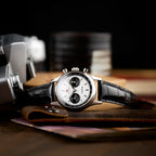 Seagull 1963 White Panda 40mm propped against a brown leather pouch beside an old camera