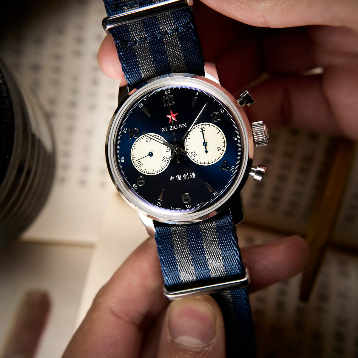 Seagull 1963 Blue Panda 42mm dial in hand over a printed Chinese page, cream subdials in view
