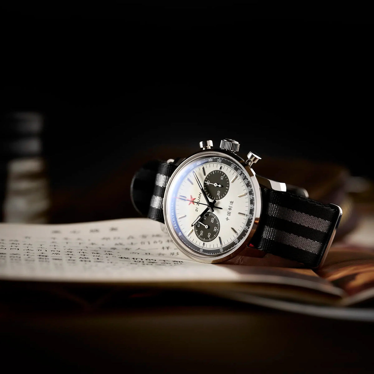 Seagull 1963 White Panda Sport 42mm lying on its side on an open Chinese book, dark background