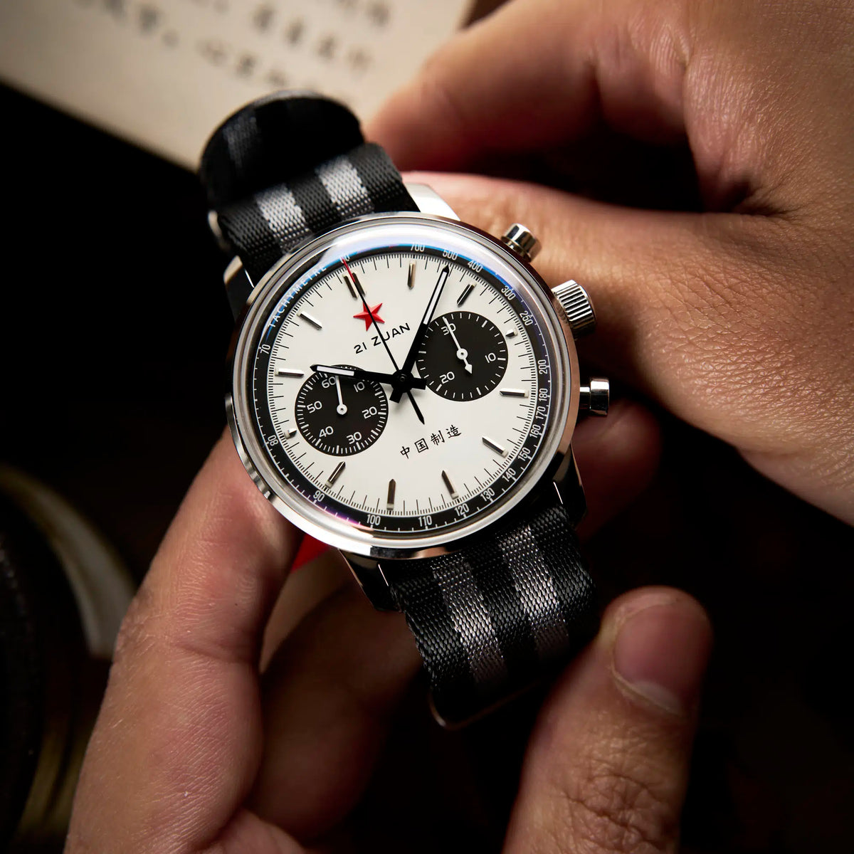 Seagull 1963 White Panda Sport 42mm cradled in two hands above a book printed in Chinese