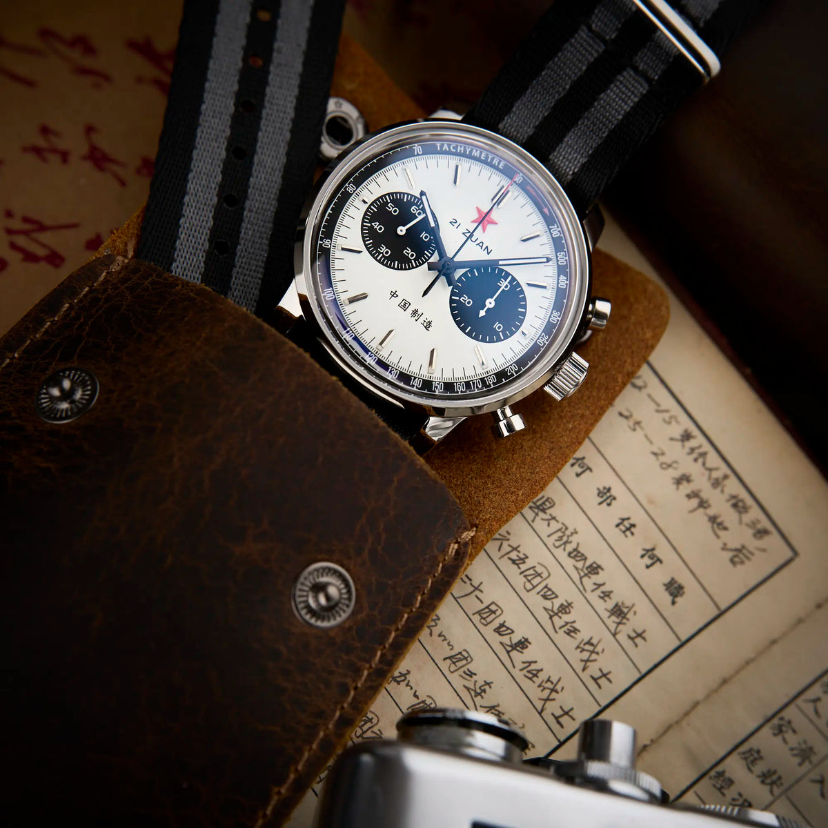 Seagull 1963 White Panda Sport 42mm tucked into a brown leather pouch on a printed page