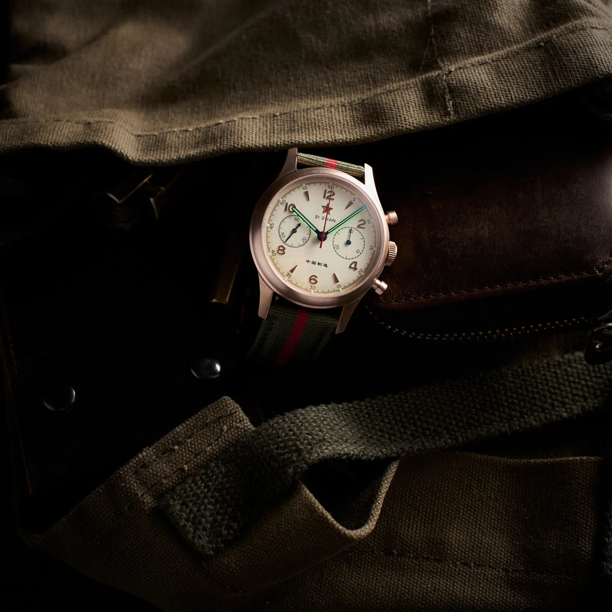 Seagull 1963 Bronze Lume 40mm lying on an olive canvas jacket with brown leather trim