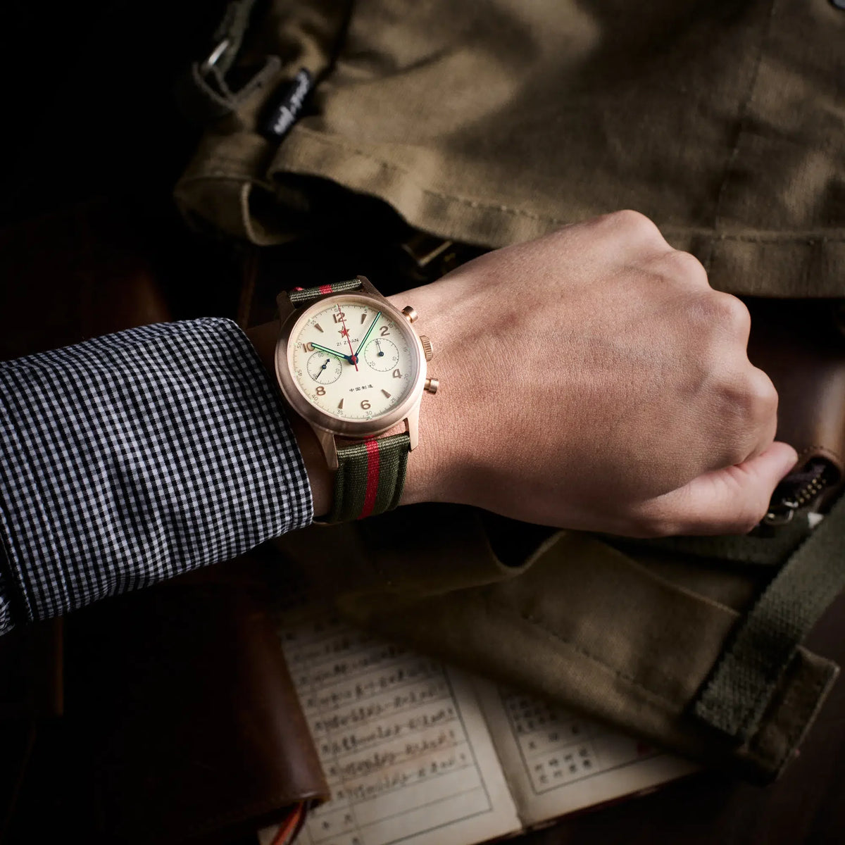 Seagull 1963 Bronze Lume 40mm on the wrist with a gingham cuff, olive canvas bag in the frame