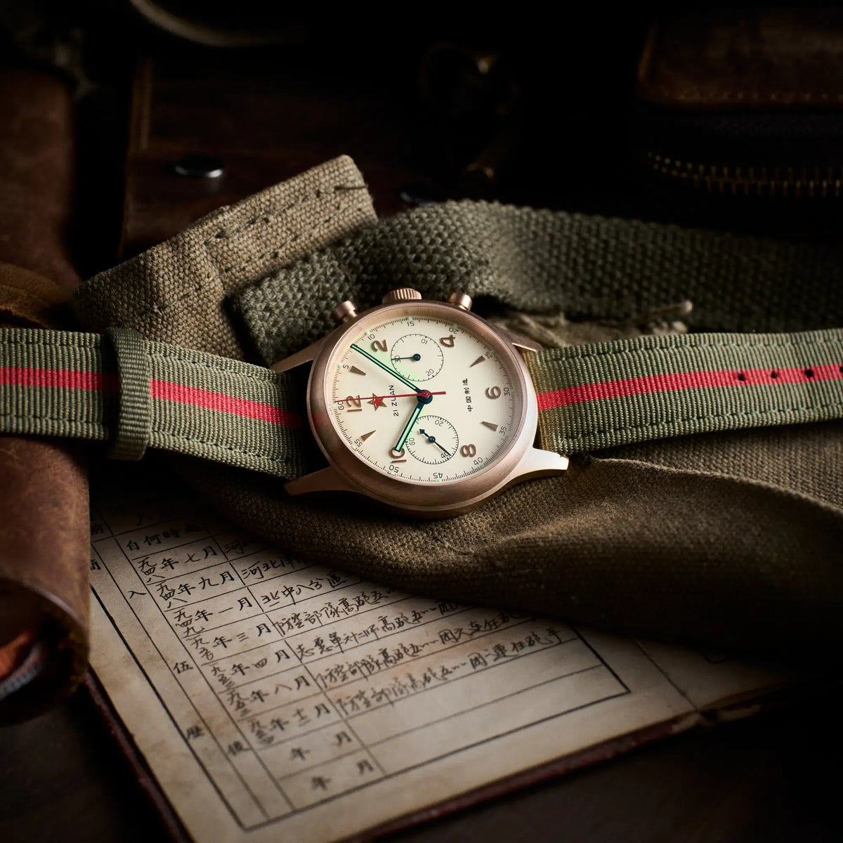 Seagull 1963 Bronze Lume 40mm across a green canvas belt on an open handwritten Chinese letter