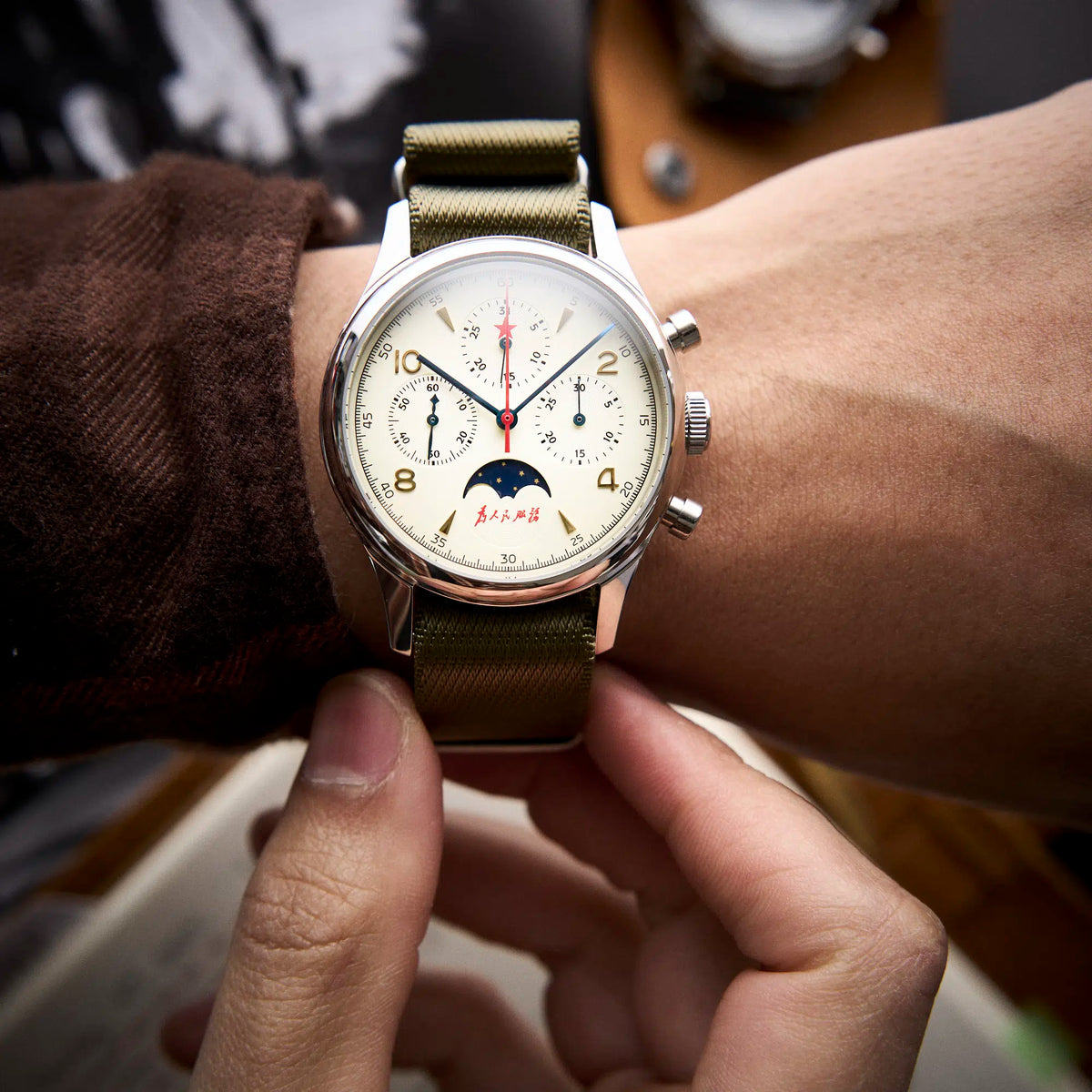 Seagull 1963 Moonphase Cream on the wrist under a brown flannel sleeve, olive nylon strap