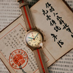 Seagull 1963 Bronze Lume flat lay on Chinese documents with a red seal, grey-beige strap with red stripe
