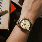 Seagull 1963 Bronze Lume on the wrist beside a Chinese book and a brass pen
