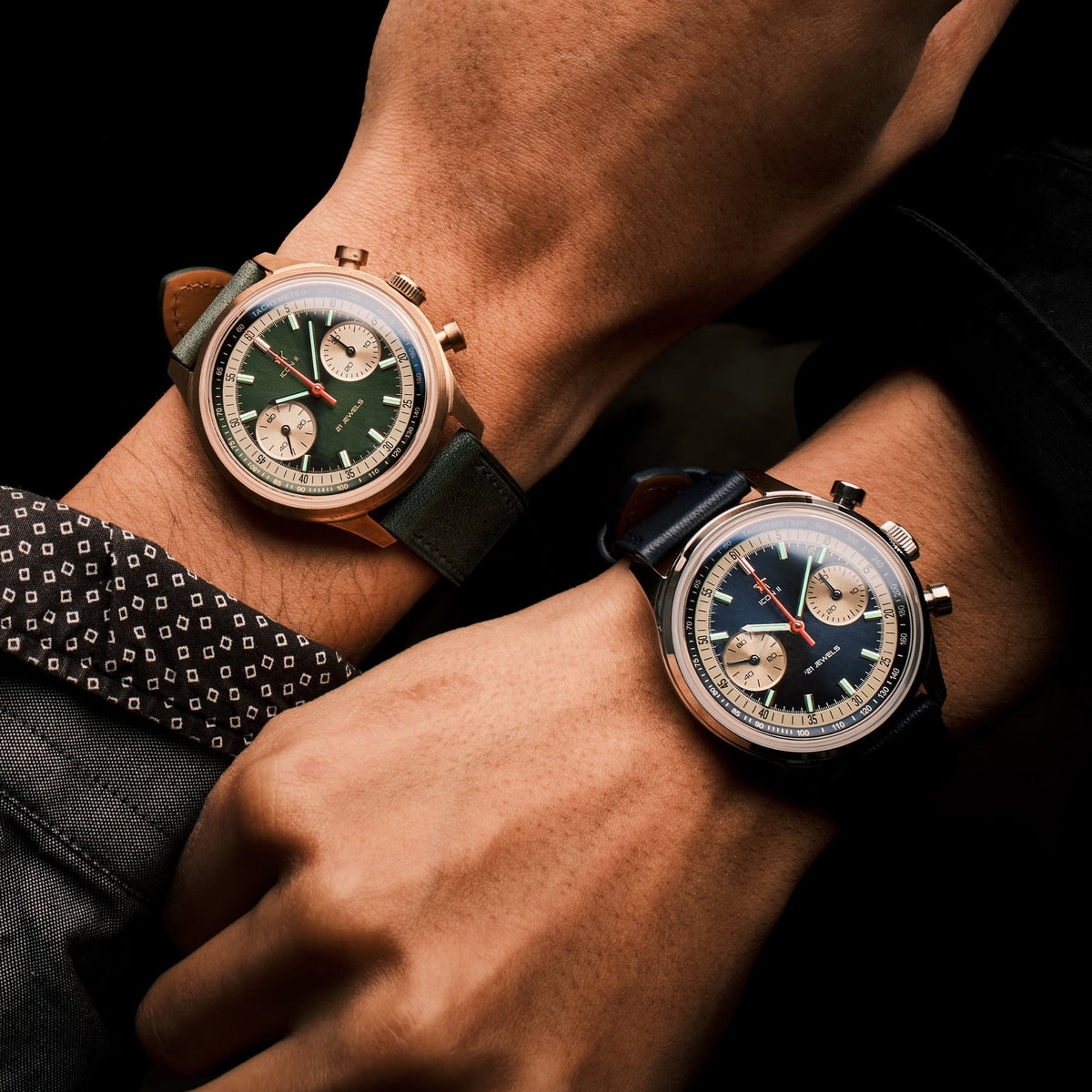 Seagull 1963 Icon II Blue and its green bronze sibling glowing on two wrists side by side